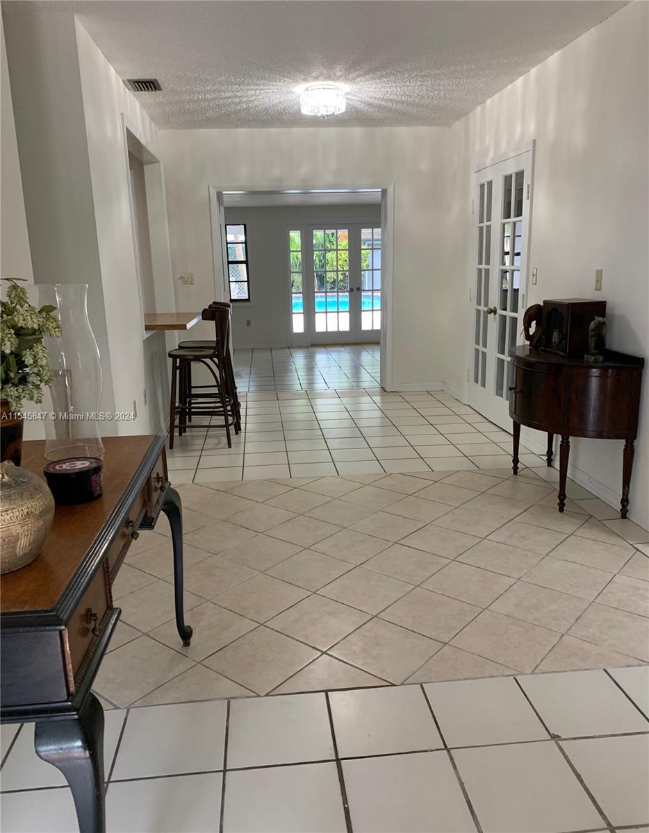 Entry with view to large open family room with french doors to patio and pool