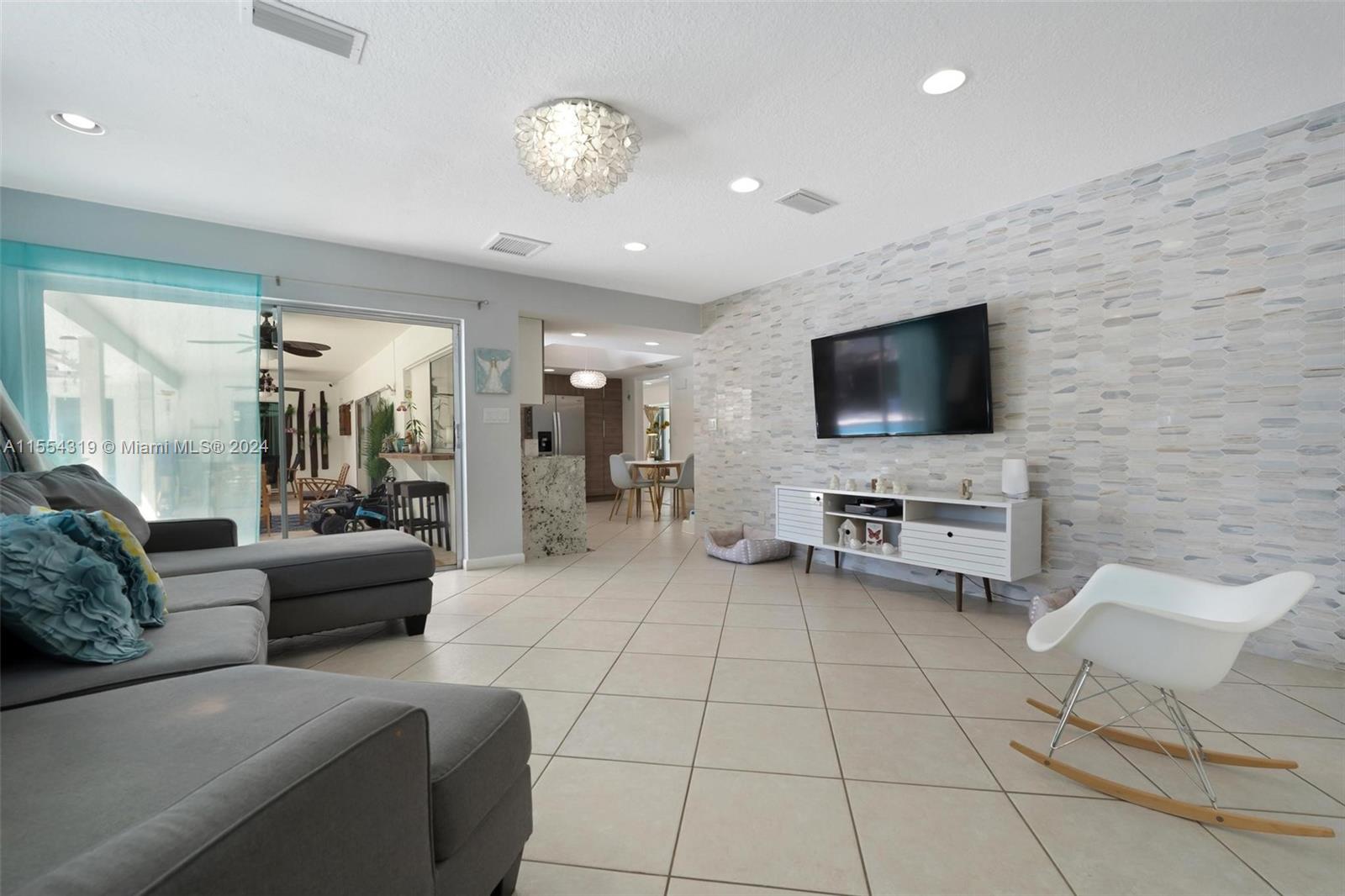 Family room just off the kitchen features a custom marble accent wall and sliding doors which lead to your backyard paradise.