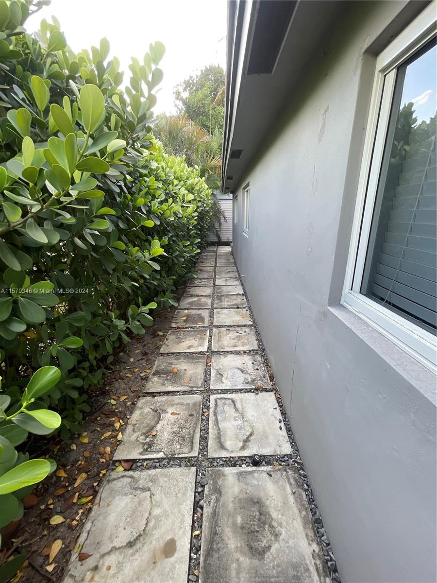 Behold the side view of this exquisitely updated home, graced with beautiful pavers that radiate sophistication. Each detail speaks of meticulous care, showcasing the effort invested in achieving an elegant aesthetic. As the eye glides over the seamless arrangement, one can't help but admire the harmonious blend of beauty and functionality, a testament to refined taste and craftsmanship.
