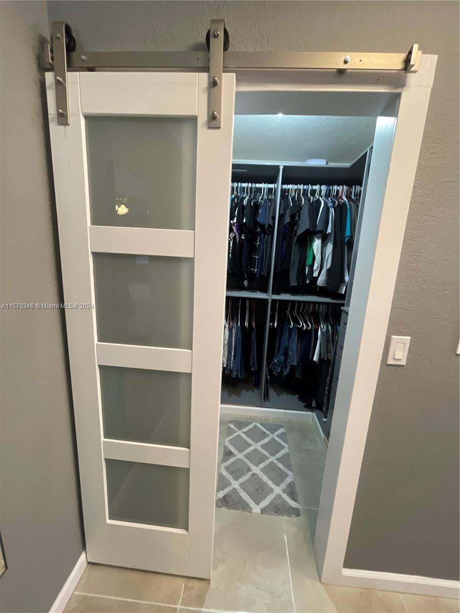 Step into opulence within the main suite's walk-in closet, where a sliding barn door reveals meticulous custom design. Experience luxury with built-in closets and a secure, built-in safe, epitomizing bespoke elegance.