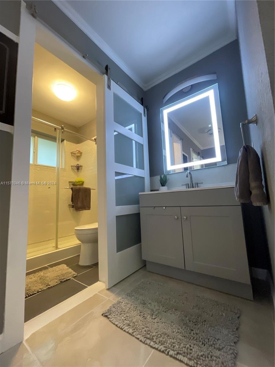 In the realm of refined indulgence lies this meticulously updated bathroom, where a breathtaking LED-enhanced mirror illuminates the space, complemented by the exquisite presence of a beautiful glass barn-style door, encapsulating timeless elegance and modern sophistication.